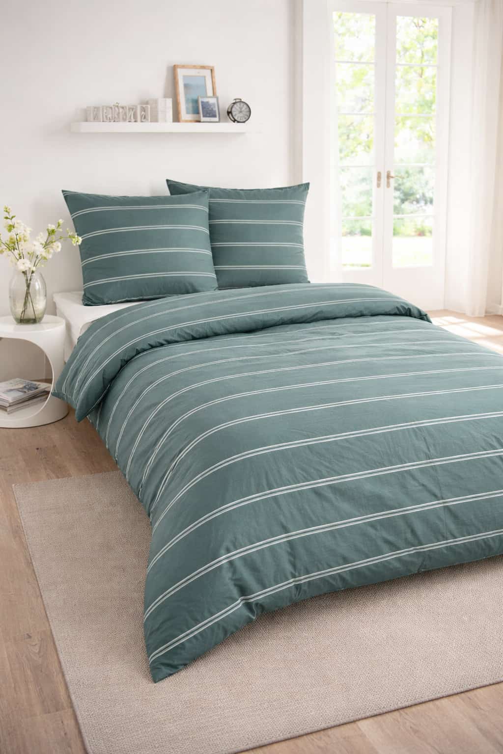 Renforcé-Bettwäsche in Dunkelgrün mit feinem gestreiften Muster auf einem weißen Bett in einem modern eingerichteten, hellen Schlafzimmer.