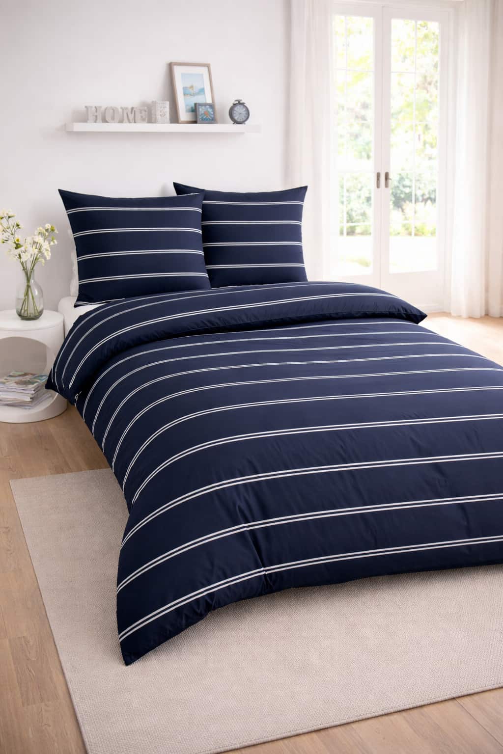 Renforcé-Bettwäsche in Dunkelblau mit feinem gestreiften Muster auf einem weißen Bett in einem modern eingerichteten, hellen Schlafzimmer.