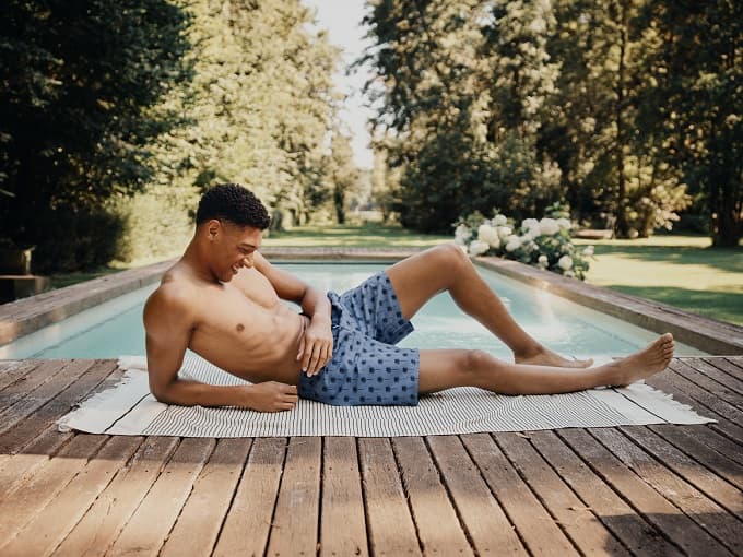Männliches Model in Badehose liegt am Poolrand