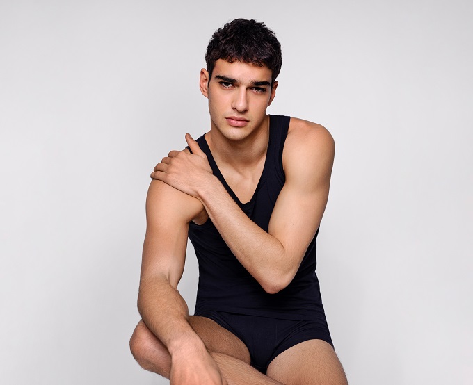 Model in einem schwarzen Herrenunterhemd mit einem Rundhals-Ausschnitt