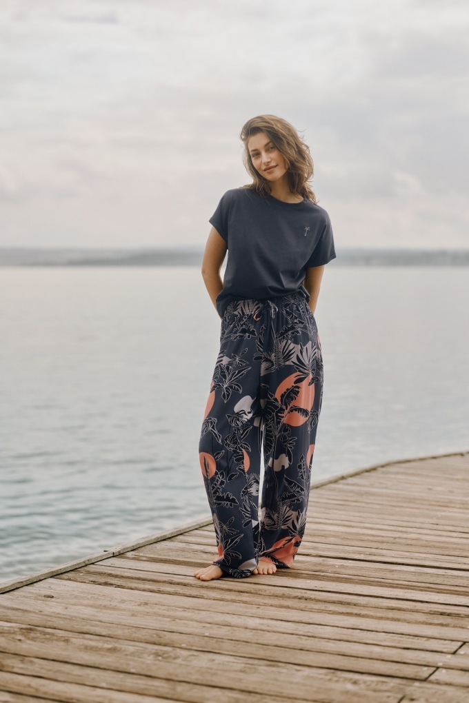 Frau in gestreifter, locker sitzender Homewear für Damen in Sondergröße – bequeme Passform für unterschiedliche Körpermaße, fotografiert in gemütlicher Wohnumgebung.
