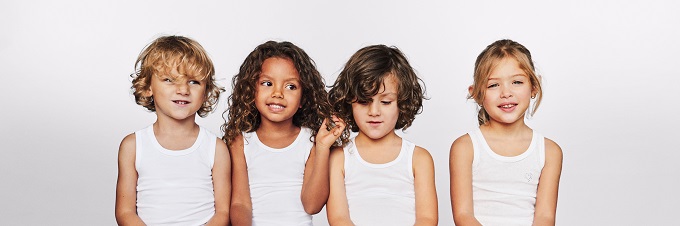 Vier Kinder, zwei Mädchen und zwei Jungen, stehen in weißen Unterhemden von SCHIESSER vor einer weißen Wand.