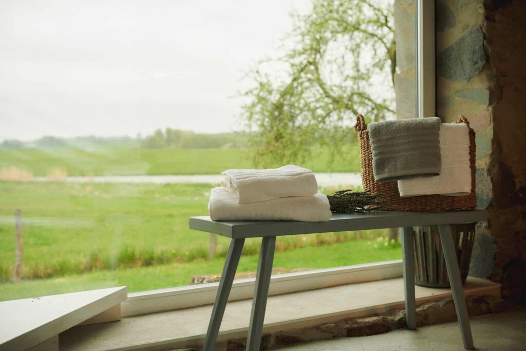 Weiße Frottee-Handtücher von SCHIESSER auf einer grünen Bank.