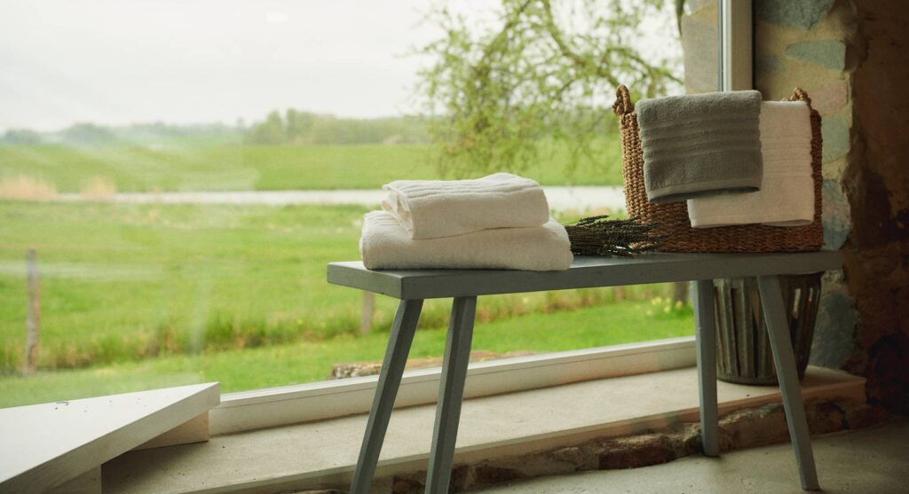 Weiße Frottee-Handtücher von SCHIESSER auf einer grünen Bank.