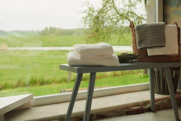 Weiße Frottee-Handtücher von SCHIESSER auf einer grünen Bank.