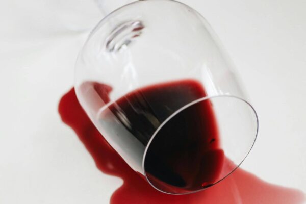 Verschütteter Rotwein aus einem umgekippten Glas auf heller Fläche.