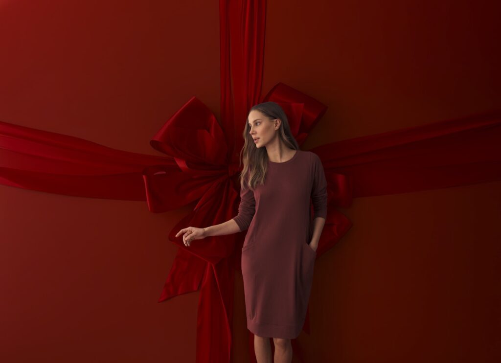 Model in einem roten Nachtkleid vor einer roten Wand mit einer roten Schleife