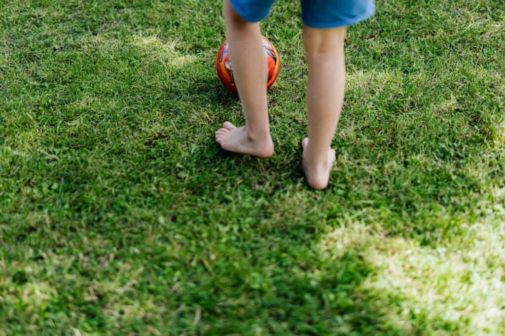 Kind spielt auf der Wiese mit einem Ball