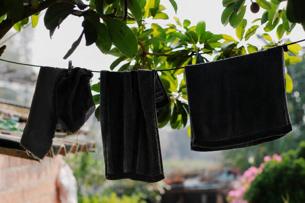 Schwarze Kleidung hängt nach dem Waschen auf einer Wäscheleine zum Trocknen.