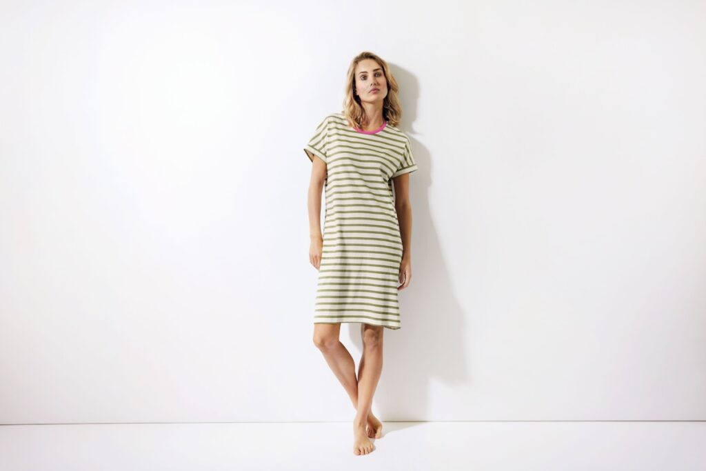 Model in einem Nachthemd vor einer weißen Wand